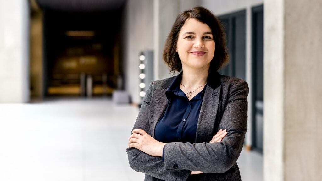 Agnieszka Hołownia-Niedzielska, Senior Solutions Consultant at Espeo Software, standing confidently in a modern office corridor.