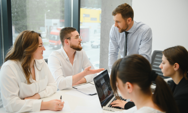 Technology team collaborating around laptops while discussing a financial platform integration.